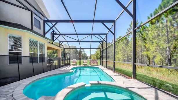 A swimming pool with a covered area and a view of a forest.