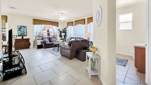 A spacious living room with a brown leather sofa, a glass coffee table, and a dining area with a table and chairs.
