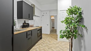 A modern kitchen with grey cabinets, a wooden countertop, and a herringbone floor pattern. - Studio 2 in Nottingham (Nottingham)