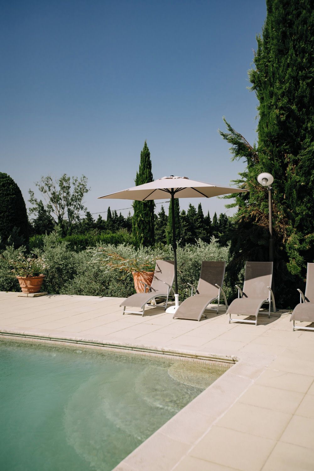 Area piscina con lettini e ombrellone, immersa nel verde.