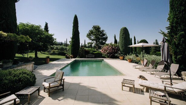 A pool area with lounge chairs and a table, surrounded by greenery and tall trees. - The Aviary - Pernes-les-Fontaines (Pernes-les-Fontaines)