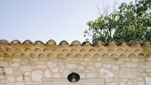 A stone building with a black door, a small wooden bench, and a potted plant. - The Aviary - Pernes-les-Fontaines (Pernes-les-Fontaines)