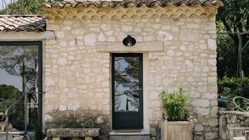 A stone building with a tiled roof, a black door, and a small porch with benches.