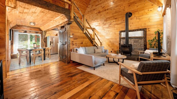 L’intérieur d’un chalet en bois chaleureux et accueillant, avec un coin repas, un canapé et une cheminée.