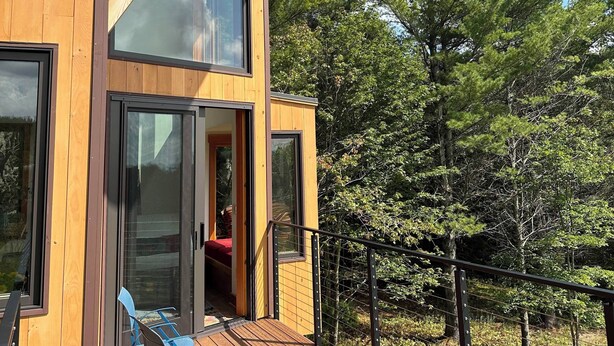 A modern wooden cabin with large windows and a deck. - Enjoy whatever winter throws at you while you relax in the hot tub with a view! (Vermontville)