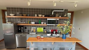 A modern kitchen with a central island, stainless steel appliances, and a tiled backsplash. - Enjoy whatever winter throws at you while you relax in the hot tub with a view! (Vermontville)
