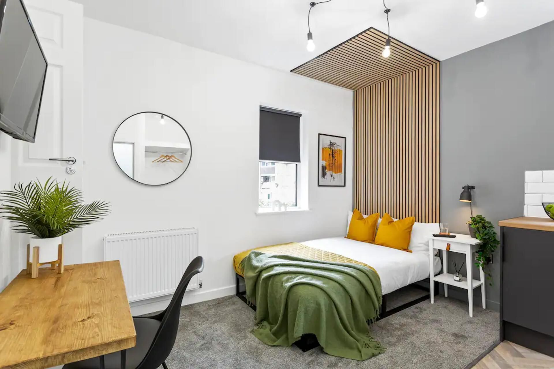 A modern bedroom with a bed, bedside table, and a desk.