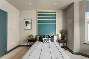 A modern bedroom with a large bed, two bedside tables, a wall-mounted shelf, a framed picture, and a window. - Studio 4 in Coventry (Coventry)