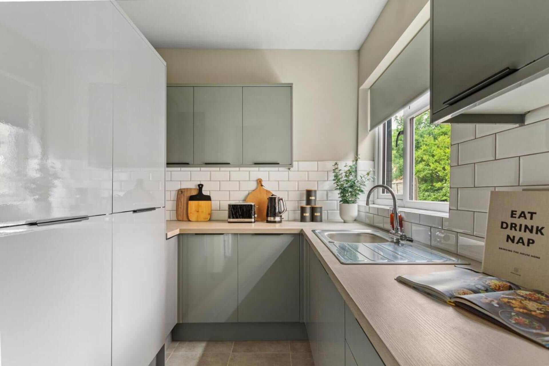 A compact kitchen with white cabinets, a wooden countertop, a sink, and a window providing natural light.