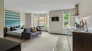 A modern hotel room with a bed, sofa, desk, and kitchenette. - Studio 4 in Coventry (Coventry)