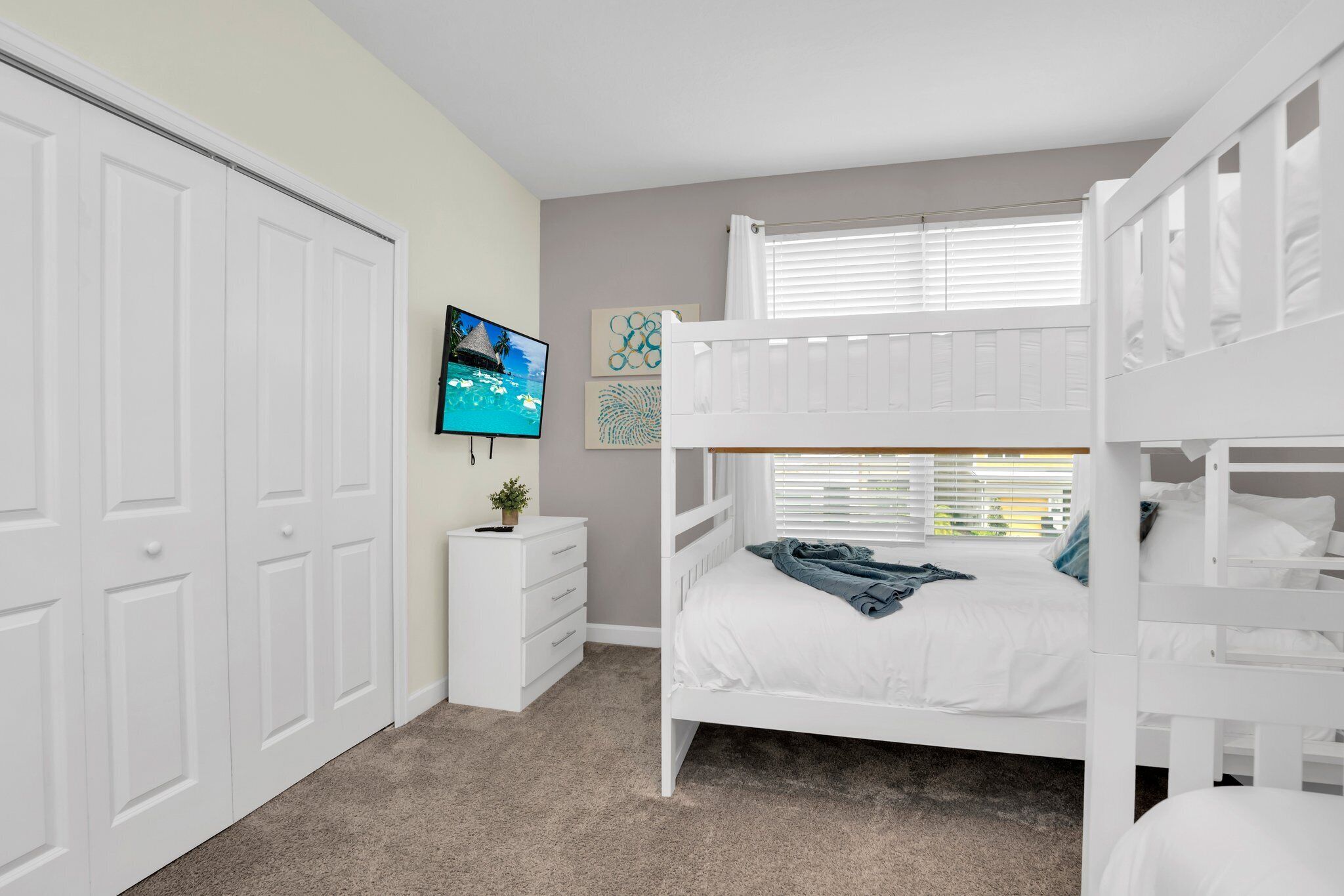 A bedroom with a bunk bed, a TV, a dresser, and a closet.
