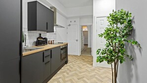 A modern kitchen with grey cabinets, a wooden countertop, and a herringbone floor pattern. - Studio 8 in Nottingham (Nottingham)