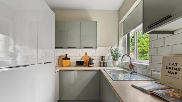 A compact kitchen with white cabinets, a wooden countertop, a sink, and a window providing natural light. - Room 5 25 Meriden Street (Coventry)