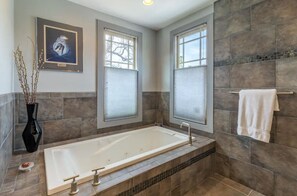 Bathroom features a bathtub, window with outdoor view, and framed artwork.