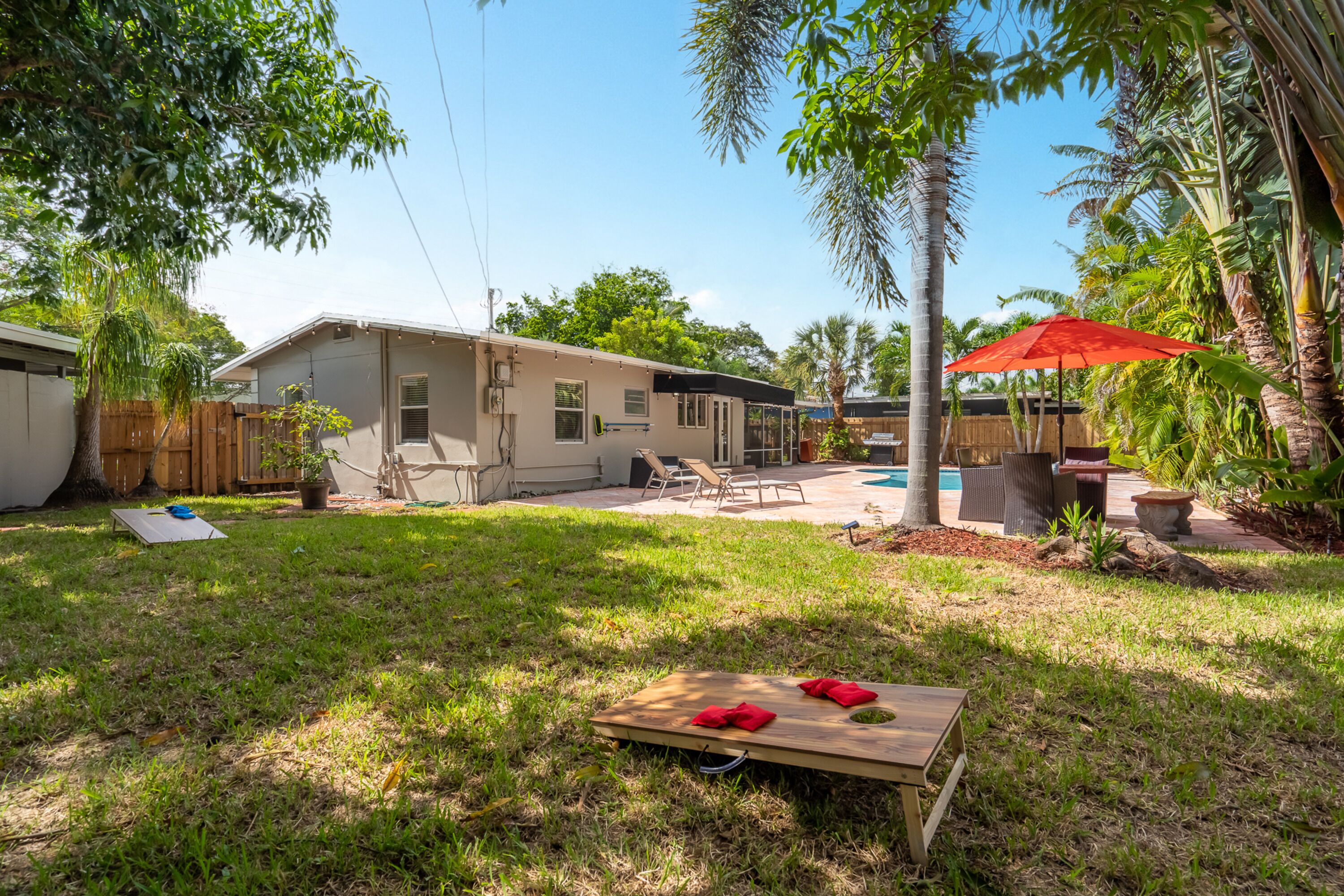 A backyard with a pool, patio furniture, and a wooden deck.