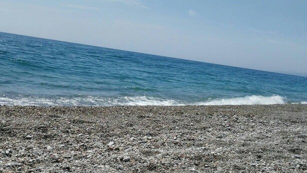 Una playa rocosa con olas rompiendo en la orilla.