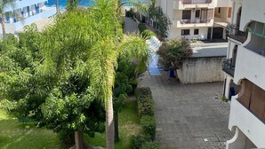 Un edificio residencial con balcones que dan a un área pavimentada y vistas al mar.