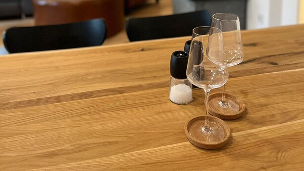 Ein Holztisch mit zwei Weingläsern und Salzstreuern.