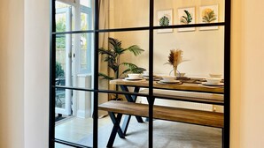 A dining area with a wooden table, chairs, and a bench. There are potted plants and framed artwork on the wall. - Stylish 3-bed House in Hornchurch - Free Parking (Hornchurch)