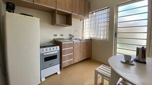 Une cuisine de taille réduite, avec des meubles en bois, un réfrigérateur blanc, une cuisinière et un évier.