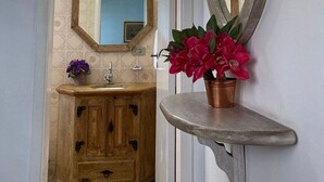 Une salle de bain avec un meuble-lavabo en bois, un miroir et une plante en pot.