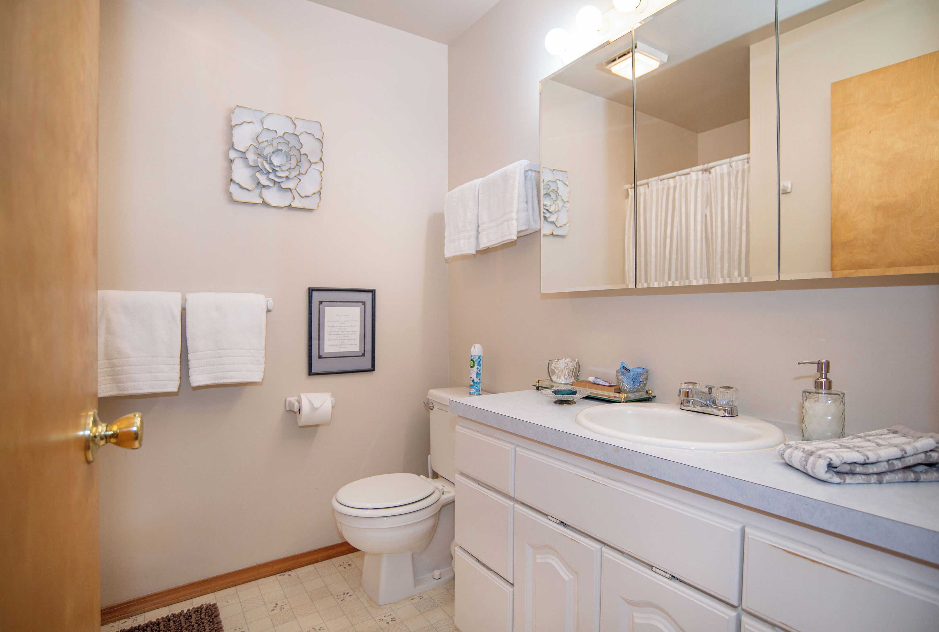 A bathroom with a toilet, sink, mirror, and towels.