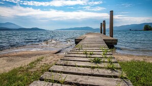 Une jetée en bois s’étendant sur une étendue d’eau calme, avec des montagnes en arrière-plan.