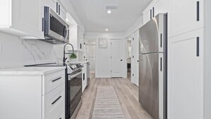 Une cuisine moderne avec des meubles blancs, des appareils en acier inoxydable et un plancher en bois.