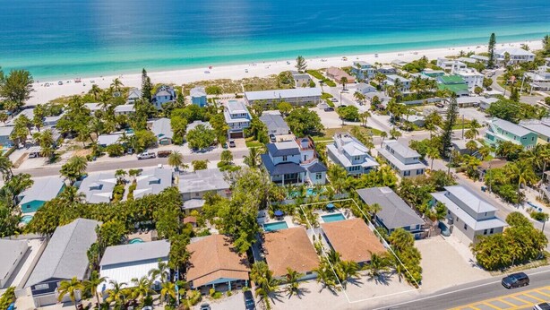Une zone résidentielle côtière avec des maisons, une plage et un ciel bleu dégagé.
