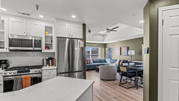 A modern kitchen with white cabinets, stainless steel appliances, and a marble countertop. - Spacious | Balcony | Central | Hosted By StayRafa (Newtown)