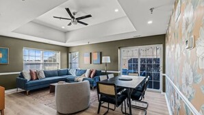 A spacious living room with a blue sofa, a dining table, and a ceiling fan. - Spacious | Balcony | Central | Hosted By StayRafa (Newtown)