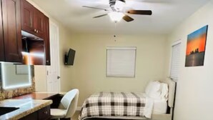A bedroom with a bed, a window, and a ceiling fan.