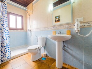 Een badkamer met toilet, wastafel, douche en spiegel.