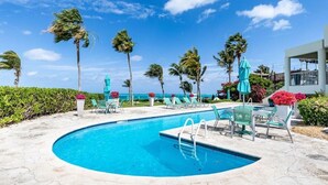 A pool area with a circular pool, lounge chairs, and umbrellas. - #4101 Fantastic 2-bed condo-Coral Gardens Resort (The Bight Settlement)