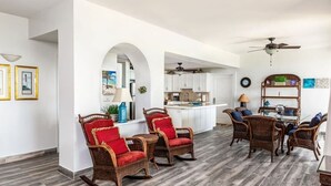A spacious living area with wicker furniture, a dining table, and a kitchen in the background. - #4101 Fantastic 2-bed condo-Coral Gardens Resort (The Bight Settlement)
