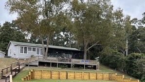 A lakeside property with a wooden deck, a small building, and a grassy area. - Life is better at the Lake 
Lakefront home that sleeps 13!  (Summerton)