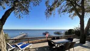 A wooden deck with lounge chairs and a table overlooking a body of water. - Life is better at the Lake 
Lakefront home that sleeps 13!  (Summerton)