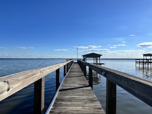 Un muelle de madera que se adentra en aguas tranquilas, con un pequeño refugio al final.