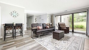 En moderne stue med sofa, to stole, sofabord og et stort vindue.