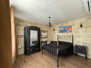 Une chambre à coucher avec un lit, une commode, un miroir et un tableau accroché au mur.