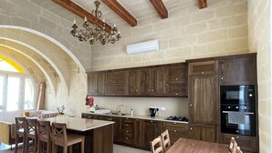A spacious kitchen with wooden cabinets, a central island, and a built-in oven. - House with pool for 10 persons, central yet quiet area (Nadur)
