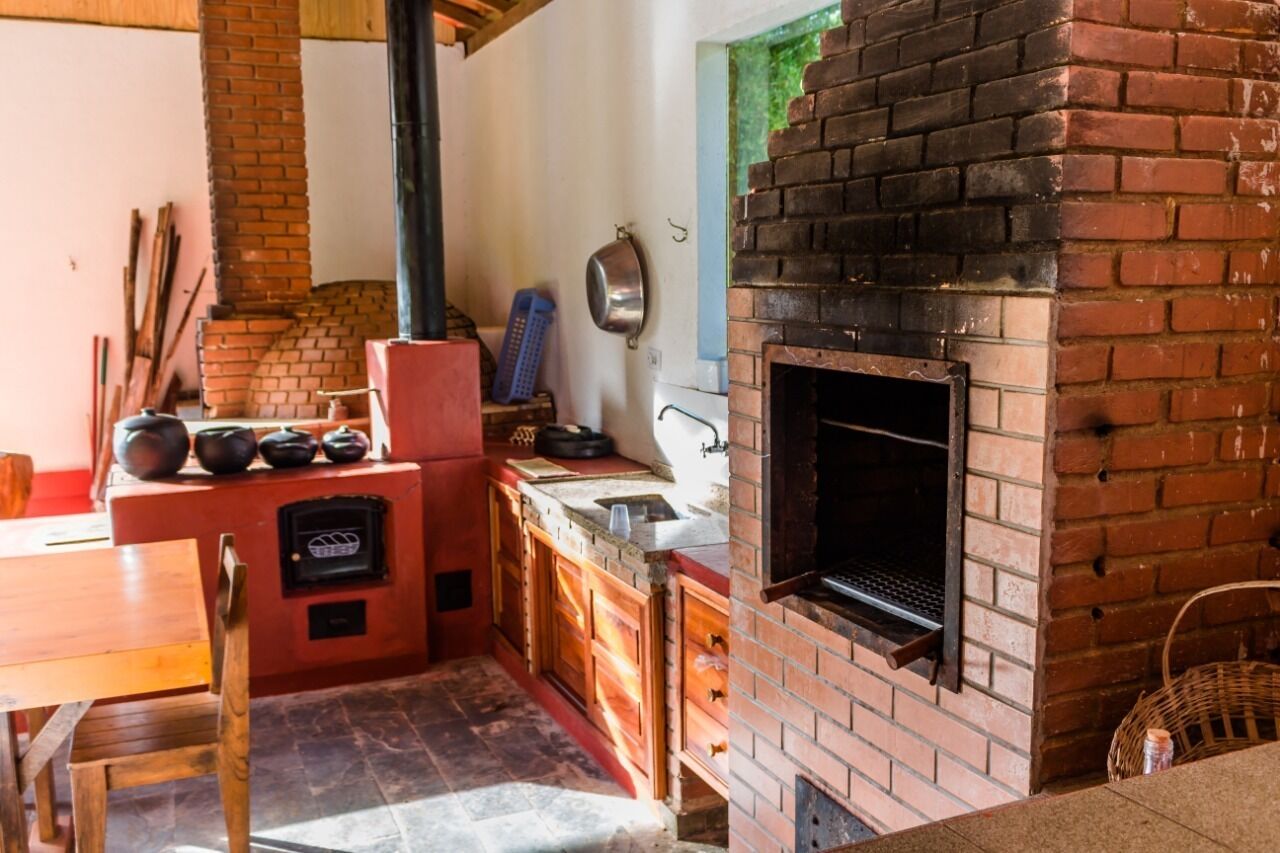 A kitchen with a brick oven, wooden cabinets, a sink, and a window.