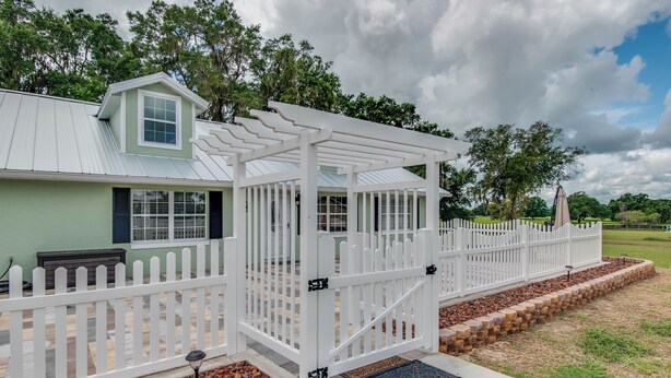 A covered porch with a white picket fence, a small porch with a window, and a door. - Green Acres House sleeps 6.  (Citra)