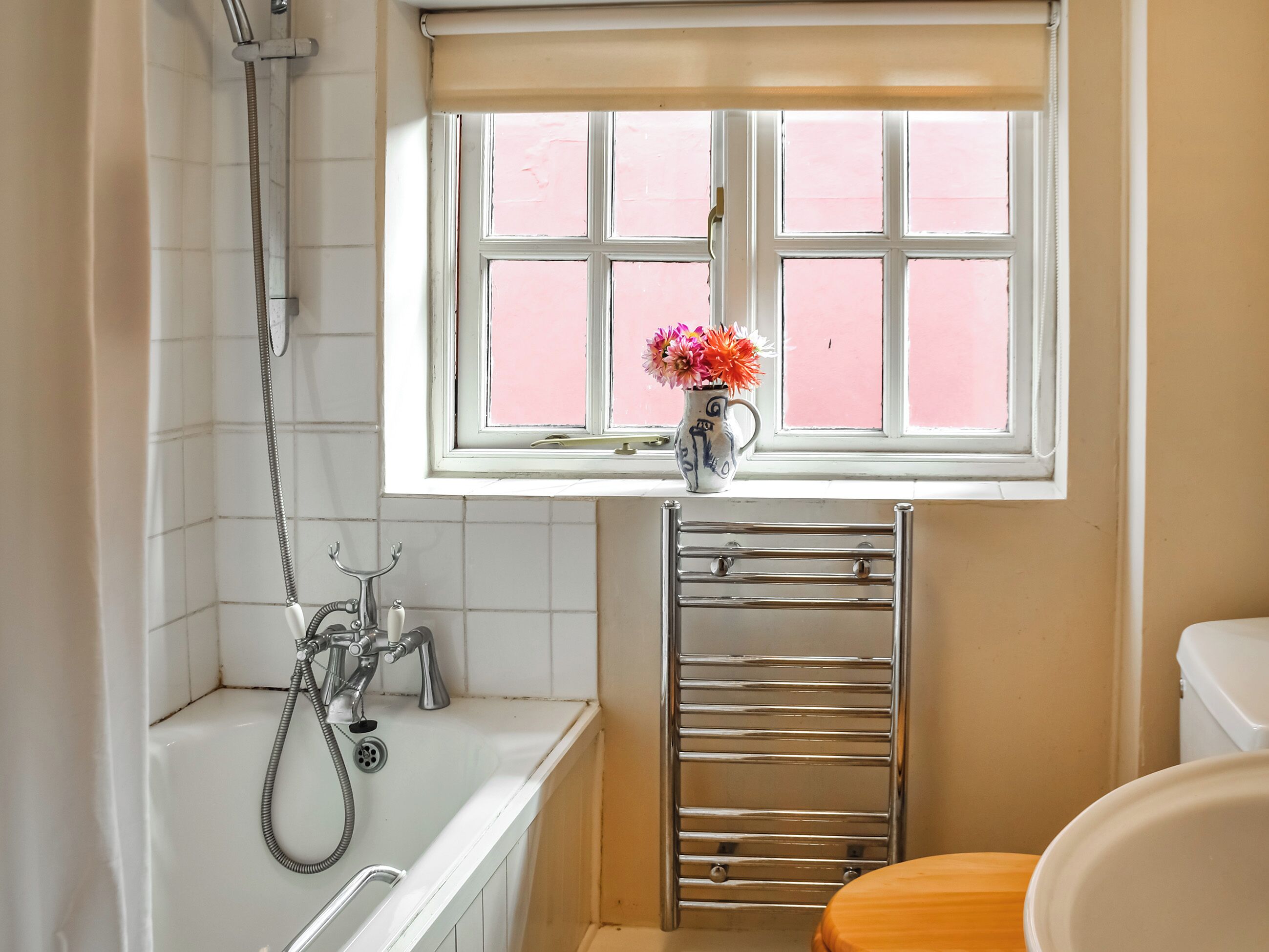 Un baño con bañera, ventana con vistas y un perchero.