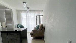 A spacious living area with a sofa, a coffee table, and a dining area with a counter. - Apartamento de 2 Habitaciones en Cali (Cali)