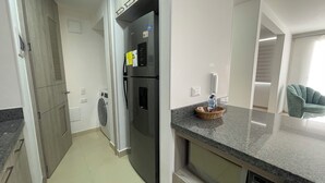 A modern kitchen with a stainless steel refrigerator, a built-in washing machine, and a granite countertop. - Apartamento de 2 Habitaciones en Cali (Cali)