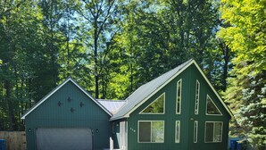 Une maison à deux étages avec un garage, une véranda et une pelouse bien entretenue.