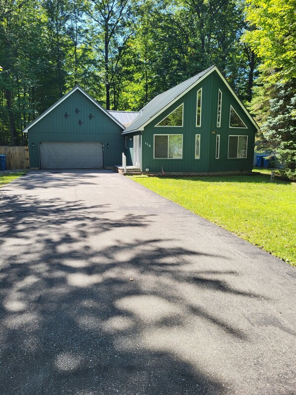Une maison à deux étages avec un garage, une véranda et une pelouse bien entretenue.