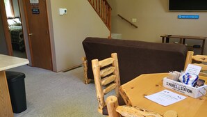 Une table à manger en bois avec des chaises, un panneau sur le mur et un escalier.