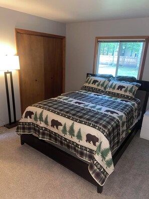 Une chambre à coucher avec un lit, une fenêtre, une lampe et une porte.